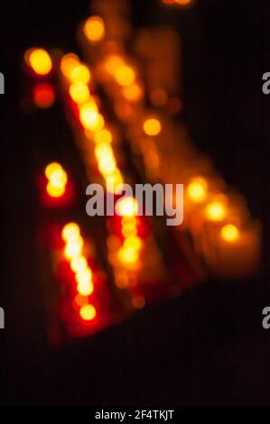 Verschwommenes Foto von Kerzen im dunklen Tempel. Bokeh. Hintergrund des Memorial Light. Gebet für kranke Geliebte. Gebet für kranke Personen Konzept. Stockfoto