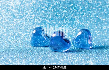 Glasblaue Herzen auf blauem Hintergrund. Konzepte der Valentinskarte, Hochzeit und Einladung. Ort für Ihren Text. Stockfoto