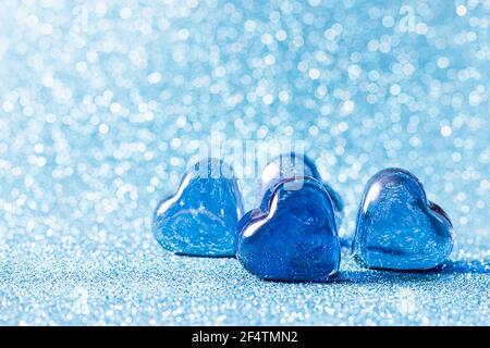 Glasblaue Herzen auf blauem Hintergrund. Konzepte der Valentinskarte, Hochzeit und Einladung. Ort für Ihren Text. Stockfoto