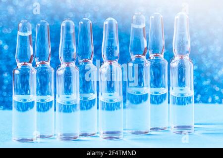 Medizinische Glasampullen auf dem Tisch auf blauem Hintergrund. Medizinische Glasampullen aus nächster Nähe. Stockfoto
