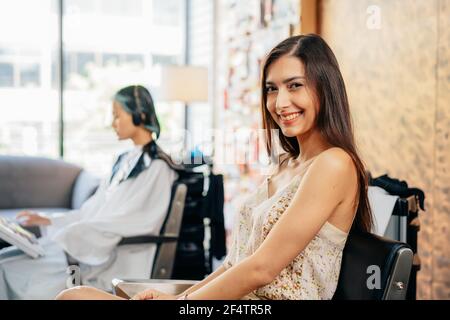 Portrait von fröhlichen jungen lächelnden kaukasischen weiblichen Kunden sitzen in Salon Stuhl im Friseurladen Blick auf Kamera nach Verwöhnung sich Mit Haarmassage Stockfoto