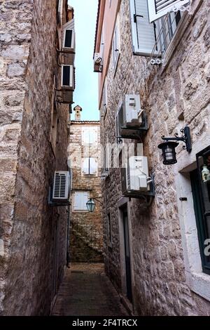 Enge gepflasterte Straße mit Treppen entlang der mittelalterlichen Steinmauer in Old Budva, Montenegro. Stockfoto