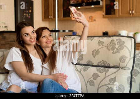 Nahaufnahme, Porträt von zwei aufgeregt Freundinnen mit Mobiltelefonen, Lachen. Gerne fröhliche weibliche Freunde Ruhe zu Hause, genießen Sie Gespräche, Spaß zu haben. Stockfoto