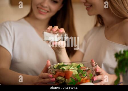 Lächelnde Schwestern bereiten gemeinsam in der Küche das Abendessen zu. Stockfoto