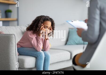 Unglückliches Mädchen, das Psychologin beim Treffen zuhört und über ihre Probleme nachdenkt Stockfoto