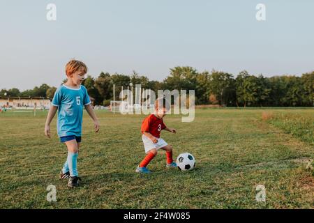 Kinder spielen Fußball. Volle Länge der jungen in Fußballkleider jagen Ball auf Fußballplatz. Stockfoto