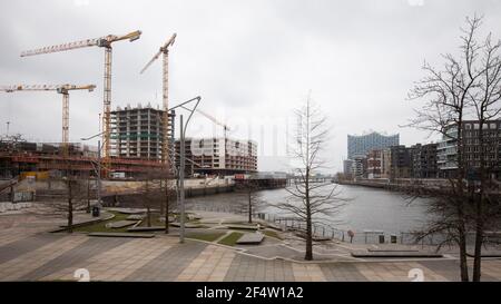 Hamburg, Deutschland. März 2021, 23rd. Blick auf die Strandkai-Baustelle im Grasbrookhafen in der HafenCity mit dem Luxus-Wohnturm "The Crown" (l). Die Silhouette der Elbphilharmonie ist im Hintergrund zu sehen. Quelle: Christian Charisius/dpa/Alamy Live News Stockfoto