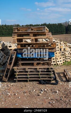 Ein Stapel Holzpaletten übereinander Mit einem Haufen Ziegelsteinschutt dahinter mit einigen Ziegelsteinen Mit Löchern Stockfoto