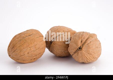 Ein Konzeptfoto von drei ganzen ungeschälten Walnüssen auf weißem Hintergrund. Stockfoto