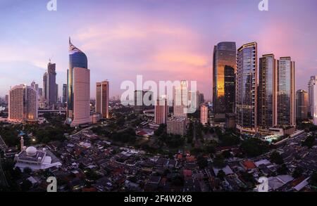 Atemberaubender Sonnenuntergang über der Skyline von Jakarta, wo moderne Büro- und Wohntürme im Kontrast zum traditionellen Dorf Kampung stehen, das in Indonesien liegt Stockfoto