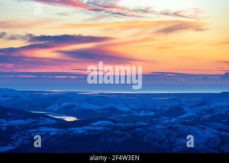 Blick über das Coniston Wasser in Richtung Küste und Walney Offshore Windpark von Red Screes, Lake District, Großbritannien mit leuchtendem Licht bei Sonnenuntergang. Stockfoto