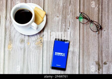 Ein Handy oder Handy auf einem Holz gelegt Tabelle mit geöffneter Screwfix-App auf dem Bildschirm Stockfoto