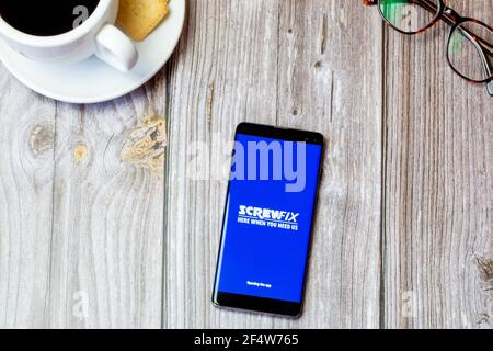 Ein Handy oder Handy auf einem Holz gelegt Tabelle mit geöffneter Screwfix-App auf dem Bildschirm Stockfoto