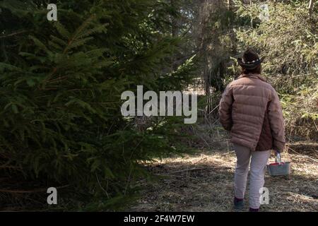 Eine Frau mit kurzen braunen Haaren trägt einen braunen Cattleman Cowboy Hut mit einer Feder und dekorativen Gürtel befestigt. London, Ontario, Kanada. Stockfoto