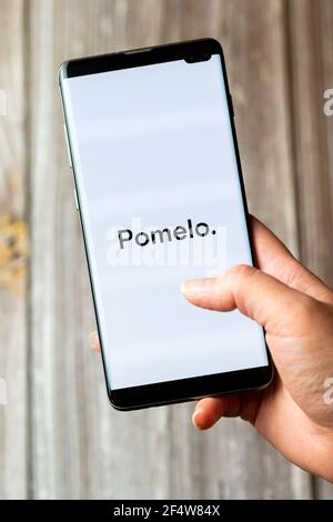 Ein Mobiltelefon oder Mobiltelefon, das in einem gehalten wird Hand mit der Pomelo App geöffnet auf dem Bildschirm Stockfoto