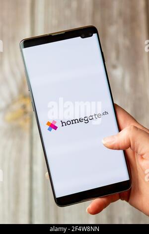 Ein Mobiltelefon oder Mobiltelefon, das in einem gehalten wird Hand mit der Homegate App auf dem Bildschirm geöffnet Stockfoto