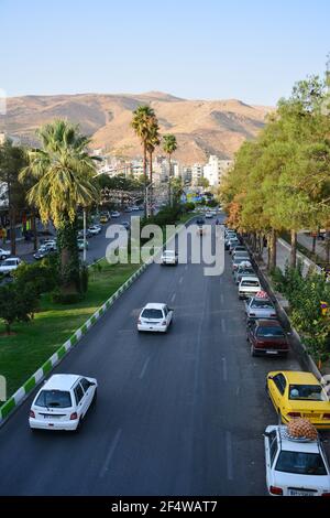 Azadi Boulevard, außerhalb des Azadi Park, in Richtung Nordosten. Verschiedene Autos sichtbar auf der Straße, sowie Bäume und Gebäude. Stockfoto