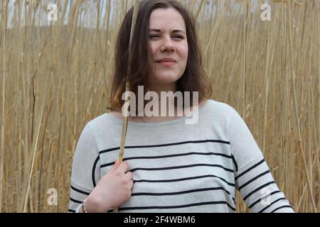 Ein junges Mädchen auf einem Feld im Freien vor dem Hintergrund von Weizen oder hohen Gras. Stockfoto