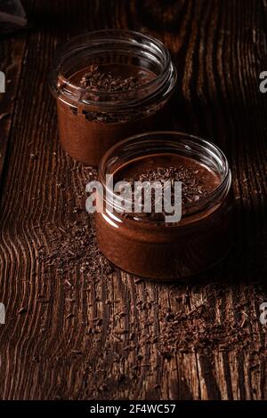 Hausgemachte dunkle Schokolade Mousse in ländlichen Gläser auf rustikalem Holz Hintergrund Stockfoto