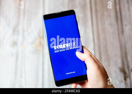 Ein Mobiltelefon oder Mobiltelefon, das in einem gehalten wird Hand mit der Screwfix App auf dem Bildschirm geöffnet Stockfoto