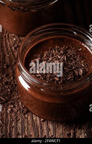 Hausgemachte dunkle Schokolade Mousse in ländlichen Gläser auf rustikalem Holz Hintergrund Stockfoto