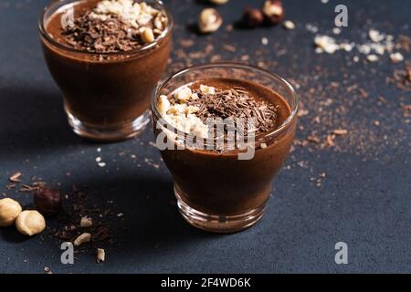 Hausgemachte dunkle Schokolade Mousse mit Haselnüssen in Gläsern auf dunkelgrauen Tisch, Nahaufnahme, Draufsicht Stockfoto