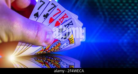 Kaukasischer Pokerspieler mit Karten in der Hand. Kings and Seven Full House Poker Spiel in der Nähe. Stockfoto