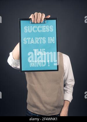 Geschäftsmann hält ein Clipboard, auf dem Erfolg geschrieben wird beginnt Im Kopf Stockfoto