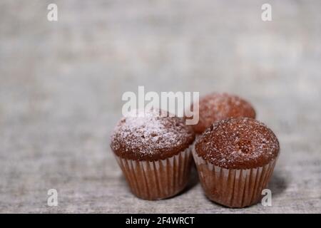 Drei Muffins Cupcakes mit Puderzucker bedeckt. Süße Bäckerei Stockfoto