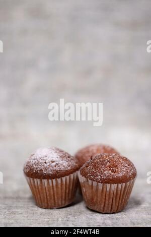 Drei Muffins Cupcakes mit Puderzucker bedeckt. Süße Bäckerei Stockfoto