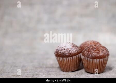 Drei Muffins Cupcakes mit Puderzucker bedeckt. Süße Bäckerei Stockfoto