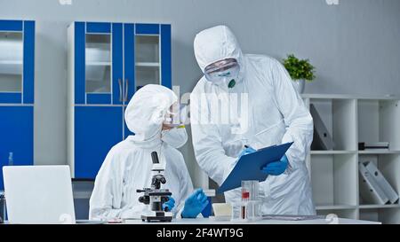 Wissenschaftler in Hazmat Anzug zeigt Forschungsergebnisse an Kollegen in Labor Stockfoto