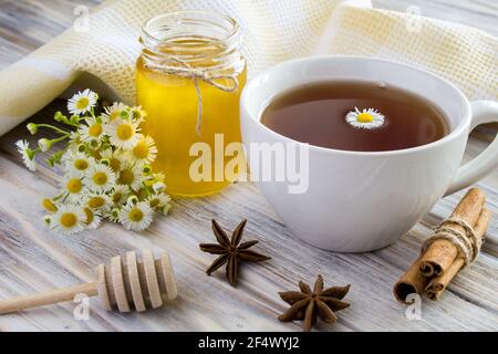 Tee, Honig, Zimt und Kamillen auf dem Holzhintergrund Stockfoto