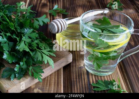Tee mit Petersilie, Honig und Zitrone auf dem Holzhintergrund Stockfoto
