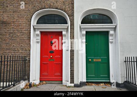 Alte Backsteinfassade im georgianischen Stil mit passenden roten und grünen Bogentüren am Merrion Square Dublin, Irland. Stockfoto