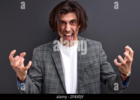 Fröhlich aufgeregt Mann stehend isoliert über schwarzem Hintergrund, feiert Erfolg, trägt formelle Anzug, schreien und gestikulieren Stockfoto