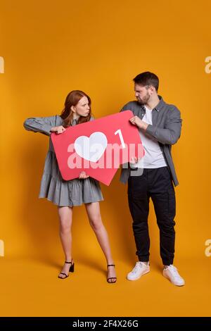 Mann Und Frau Kämpfen Um Aufmerksamkeit, Halten Wie Zeichen In Händen, Kann Nicht Teilen, Argumentieren, Isoliert Auf Orange Hintergrund Stockfoto