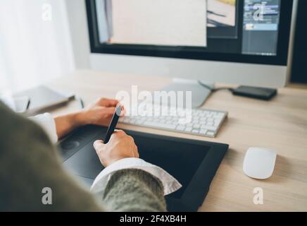 Weibliche Hände mit einem Grafiktablett mit Eingabestift und moderner Computertastatur zum Zeichnen von Kunstwerken. Grafikdesign, digitale Kunst oder freiberufliche Arbeit Stockfoto
