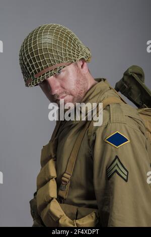 Männlicher Künstler in Militäruniform des amerikanischen Rangers von Die Periode des Zweiten Weltkriegs posiert auf einem grauen Hintergrund Stockfoto
