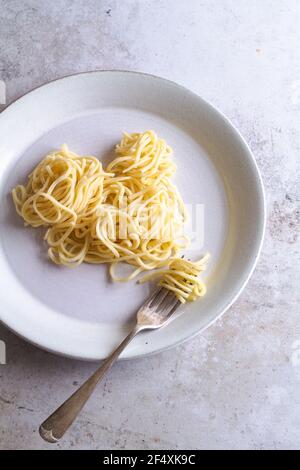 Einfache frische Spaghetti mit einer Gabel auf einem Teller. Stockfoto