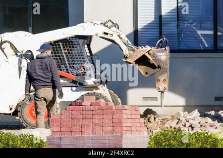 Santa Clara, CA - 25. Februar 2020: Bauarbeiter mit Baggerausrüstung, die einen neuen gemauerten Gehweg vor einem Wohnhaus einbauten. Stockfoto