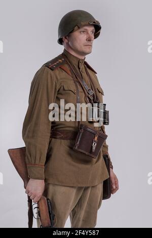 Ein männlicher Schauspieler in der Uniform eines Offiziers und eines Helms der sowjetischen Armee während des Zweiten Weltkriegs mit einem Gewehr in den Händen Stockfoto