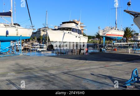 Ein Mann, der mit einer Waschmaschine an der Unterseite einer Motoryacht auf Böcken in der Santander Marina Cantabria Spanien arbeitet Stockfoto