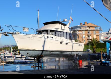 Ein Mann, der mit einer Waschmaschine an der Unterseite einer Motoryacht auf Böcken in der Santander Marina Cantabria Spanien arbeitet Stockfoto