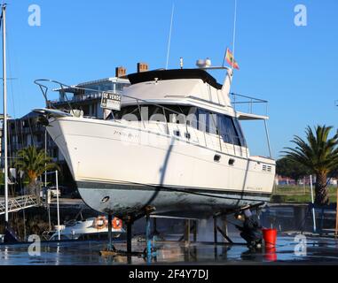 Ein Mann, der mit einer Waschmaschine an der Unterseite einer Motoryacht auf Böcken in der Santander Marina Cantabria Spanien arbeitet Stockfoto