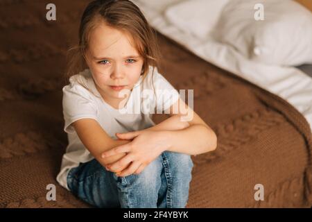 Top Nahaufnahme Ansicht von verstört schöne kleine Mädchen mit nassen Augen von Tränen sitzt auf dem Bett im Schlafzimmer und Blick auf die Kamera. Stockfoto