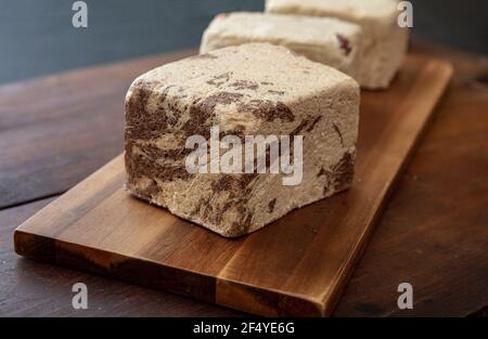 Halva Kakao und Sonnenblumenkerne Stücke auf Holztisch Hintergrund. Schokolade Halvah oder Halwa, traditionelle Dessert-Konfektion auch mit Sesam-Tah gemacht Stockfoto