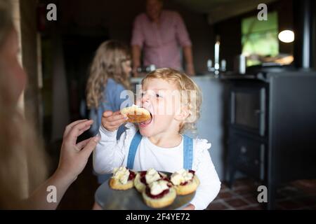 Cute begierig Mädchen essen süße Gebäck zu Hause Stockfoto