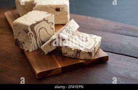 Halva Kakao und Sonnenblumenkerne Stücke auf Holztisch Hintergrund. Schokolade Halvah oder Halwa, traditionelle Dessert-Konfektion auch mit Sesam-Tah gemacht Stockfoto