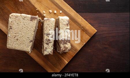 Halva-Kakao und Tahini. Sesam halvah auch bekannt Halwa Stücke mit Schokolade auf Holztisch Hintergrund, Draufsicht. Traditionelle Dessert Konfektion auch Stockfoto